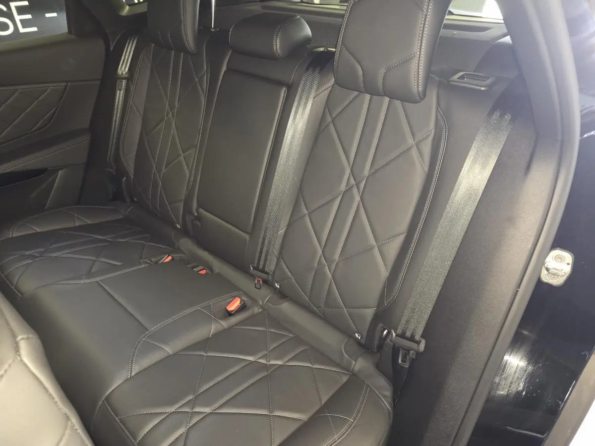 Vue intérieure des sièges arrière en cuir noir matelassé du DS7 Crossback E-Tense 2024, avec ceinture de sécurité et porte ouvert.