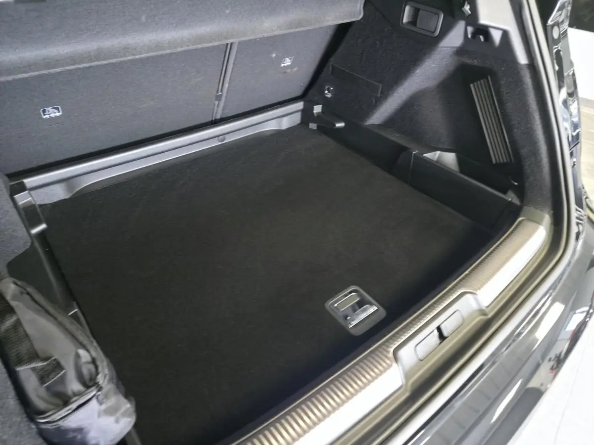Coffre ouvert vu de trois quarts arrière droit du DS7 Crossback noir avec seuil de coffre chromé et tapis noir.