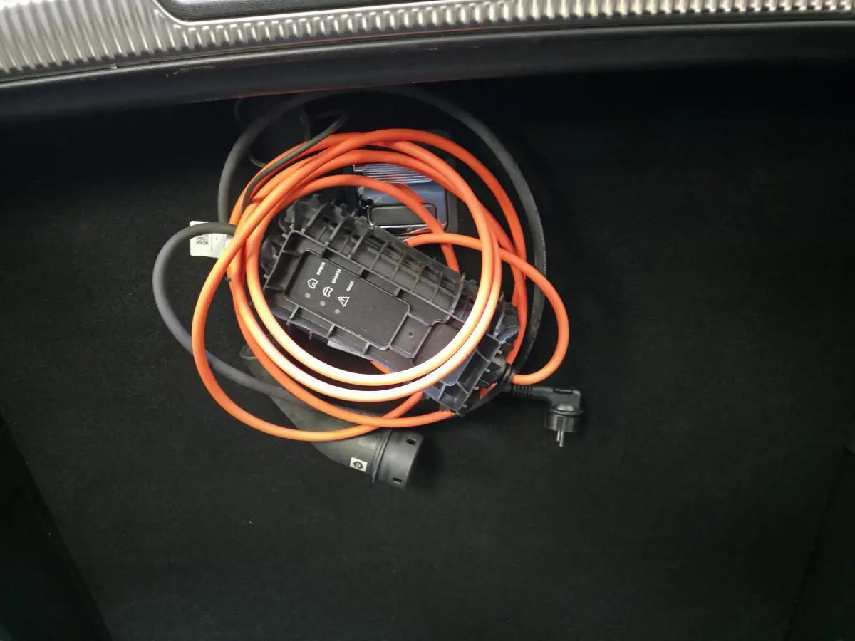 Câble de recharge orange enroulé dans le coffre noir du DS7 Crossback E-Tense 2024.