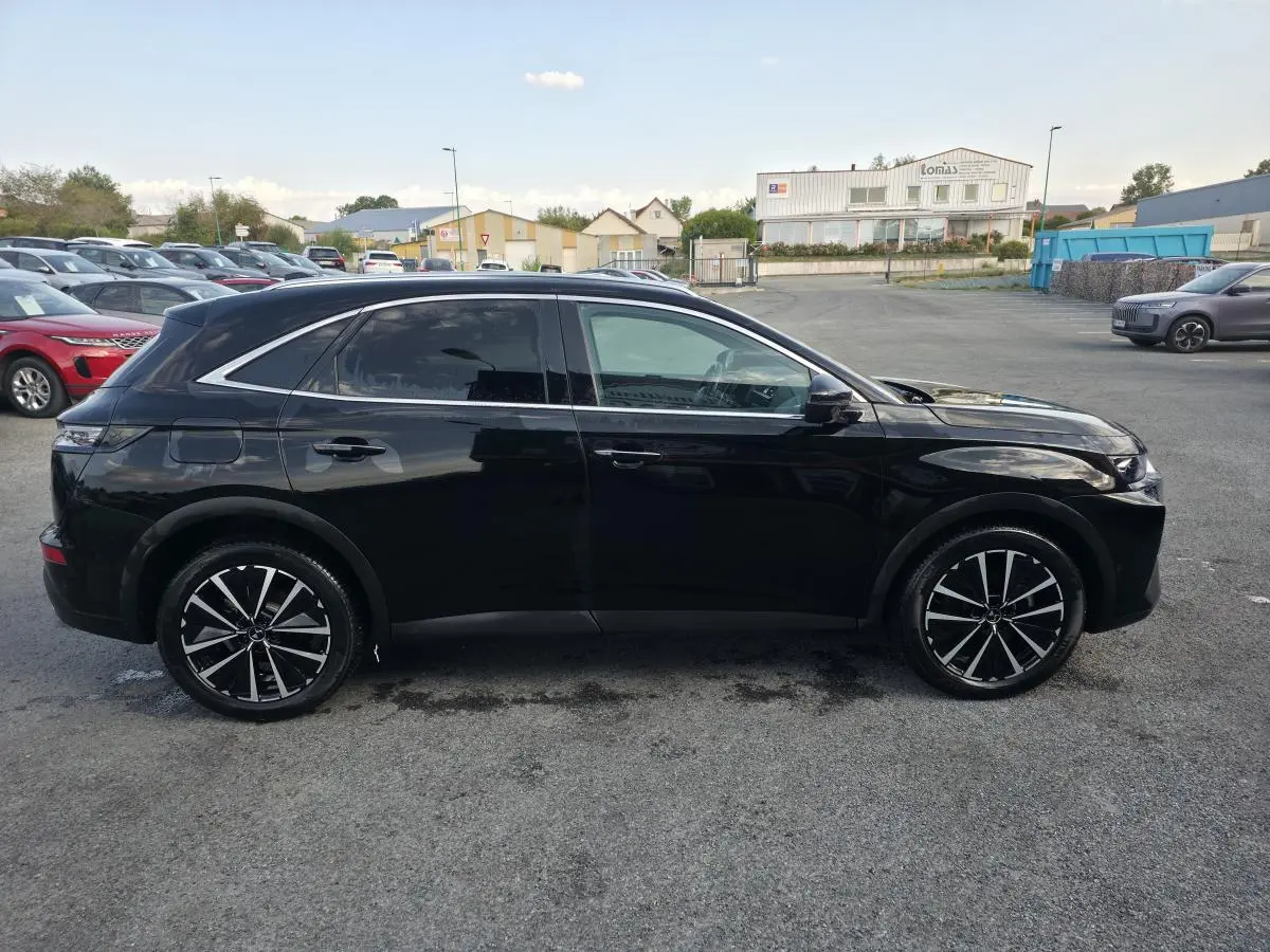 Vue latérale droite du SUV DS7 Crossback E-Tense 225 noir avec jantes alliage 19 pouces sur parking extérieur.