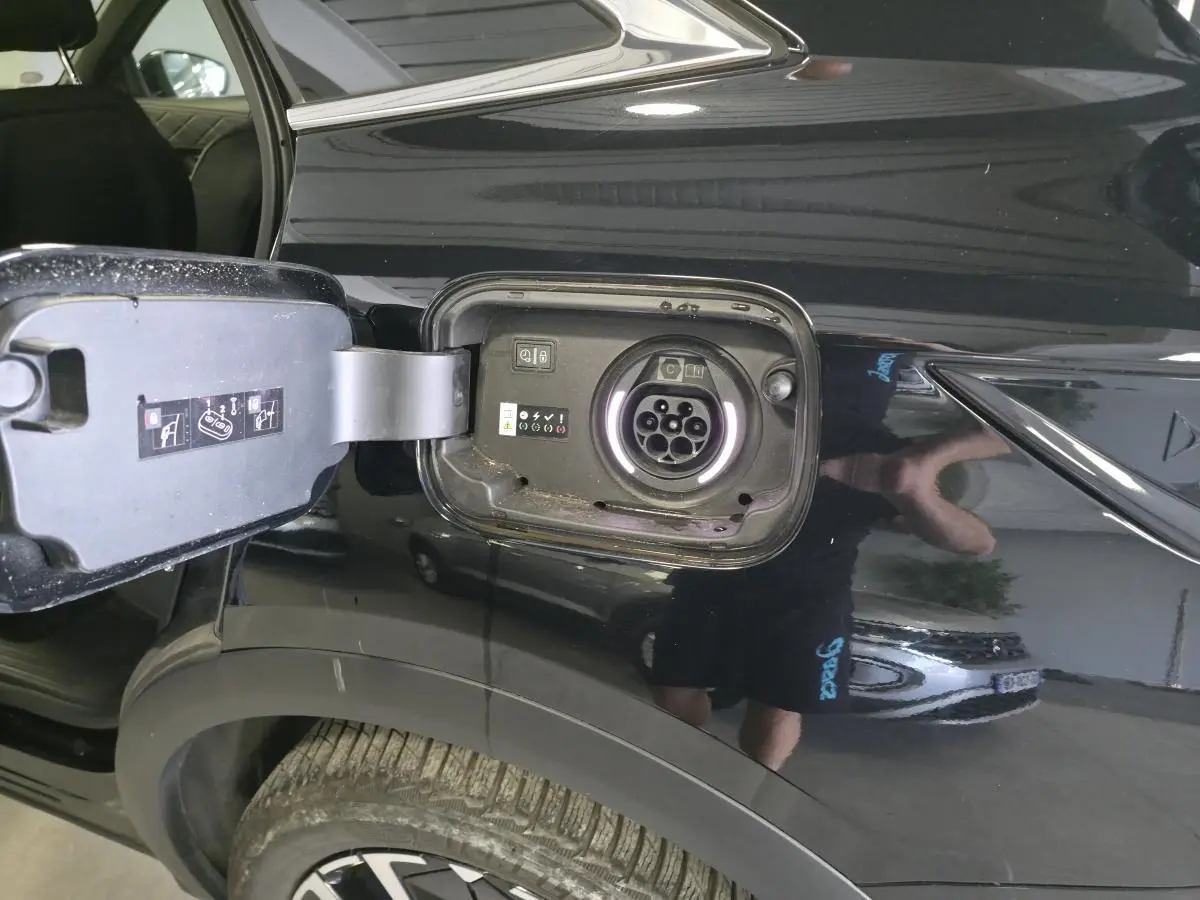 Détail de la trappe de recharge ouverte côté arrière droit sur DS7 Crossback E-Tense noir brillant.