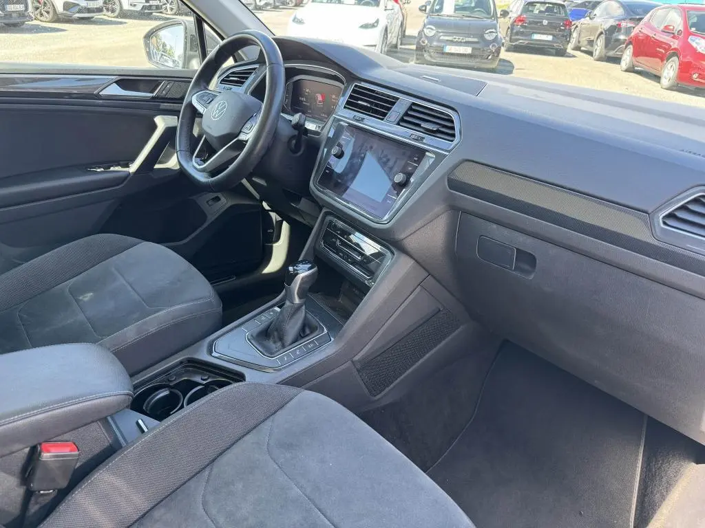 Intérieur avant du Volkswagen Tiguan gris, vue côté conducteur montrant le tableau de bord et la console centrale avec boîte auto.