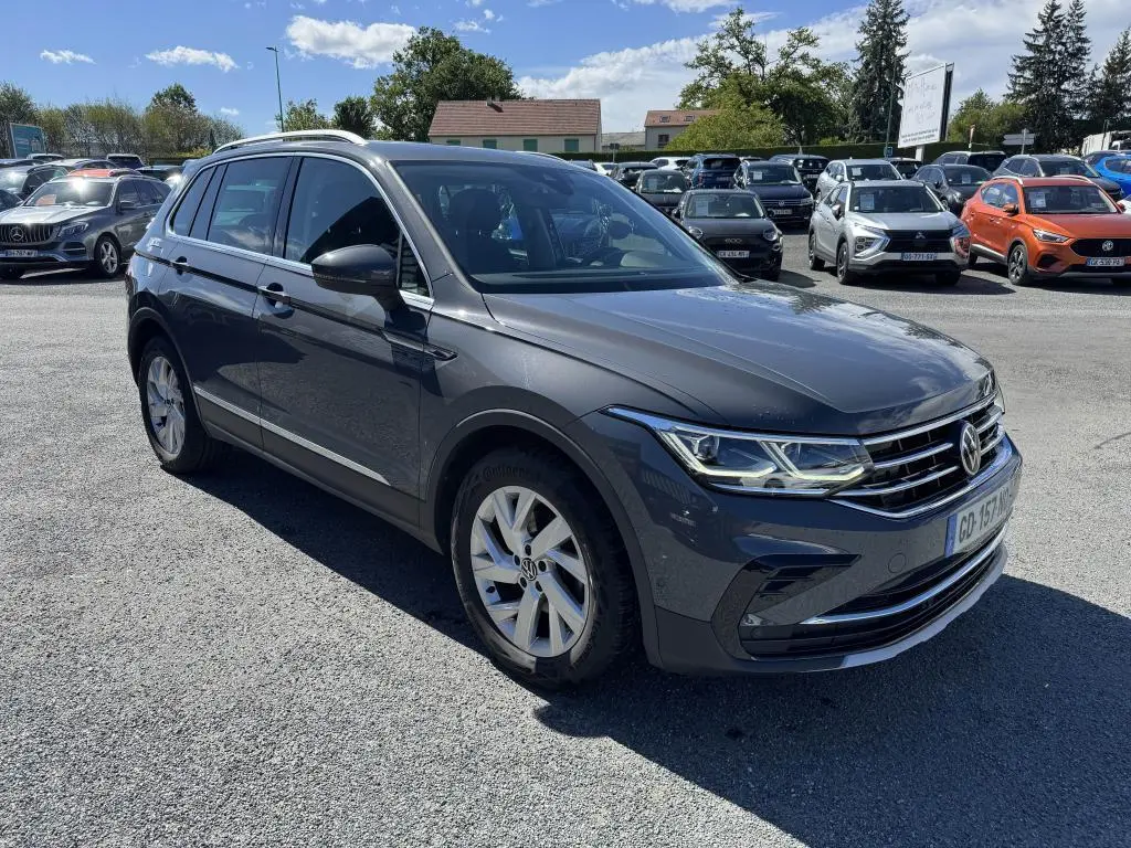 Volkswagen Tiguan gris 3/4 avant droit, avec jantes alliage et calandre chromée, stationné en extérieur.