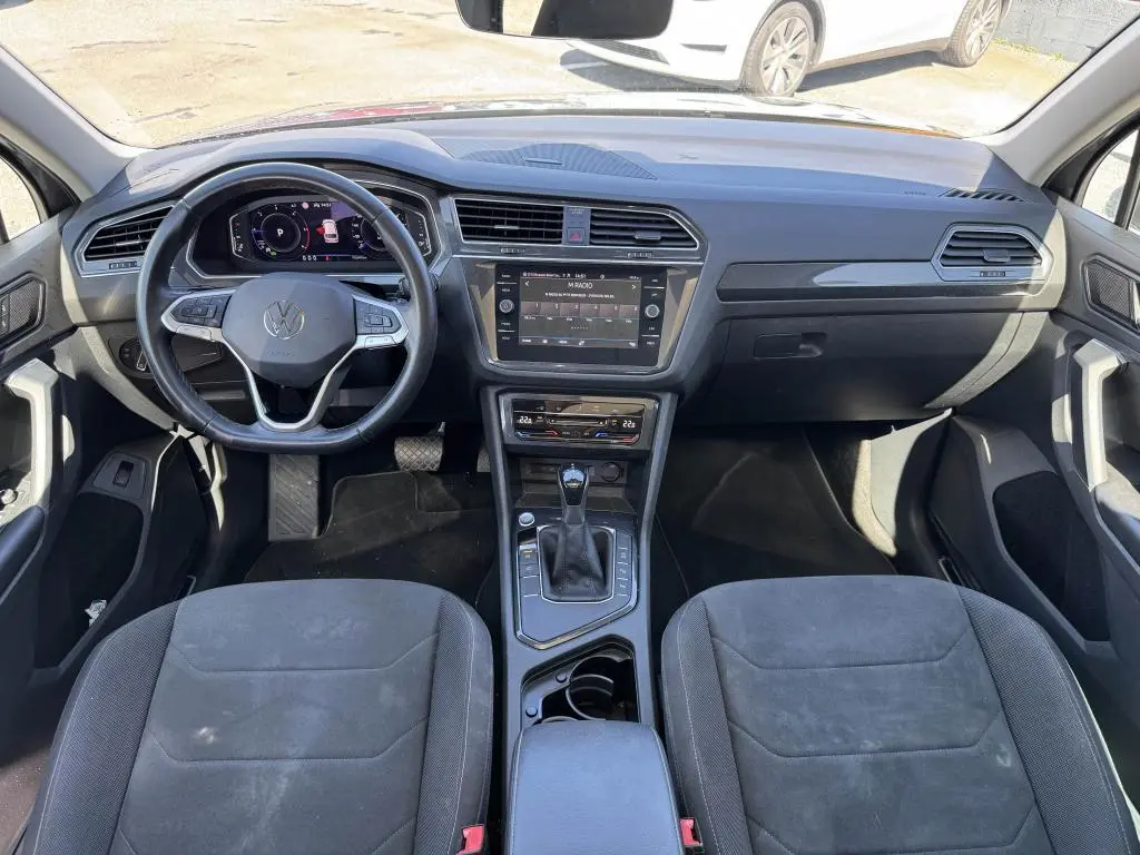 Intérieur avant du Volkswagen Tiguan 2021, tableau de bord noir avec volant multifonctions et console centrale moderne.