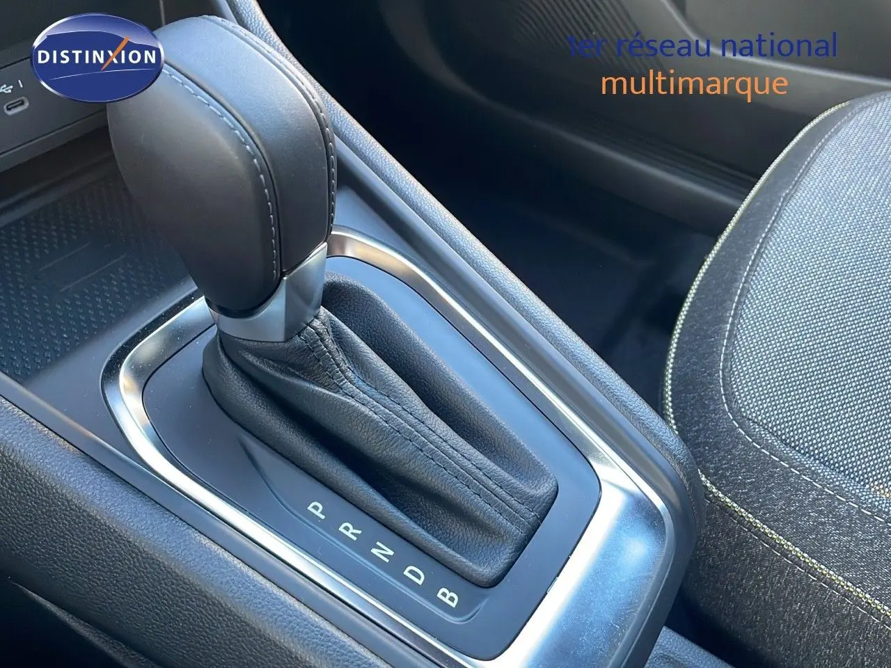 Le levier de vitesses automatique en cuir noir du Renault Captur E-Tech hybride, avec siège tissu gris visible à côté.