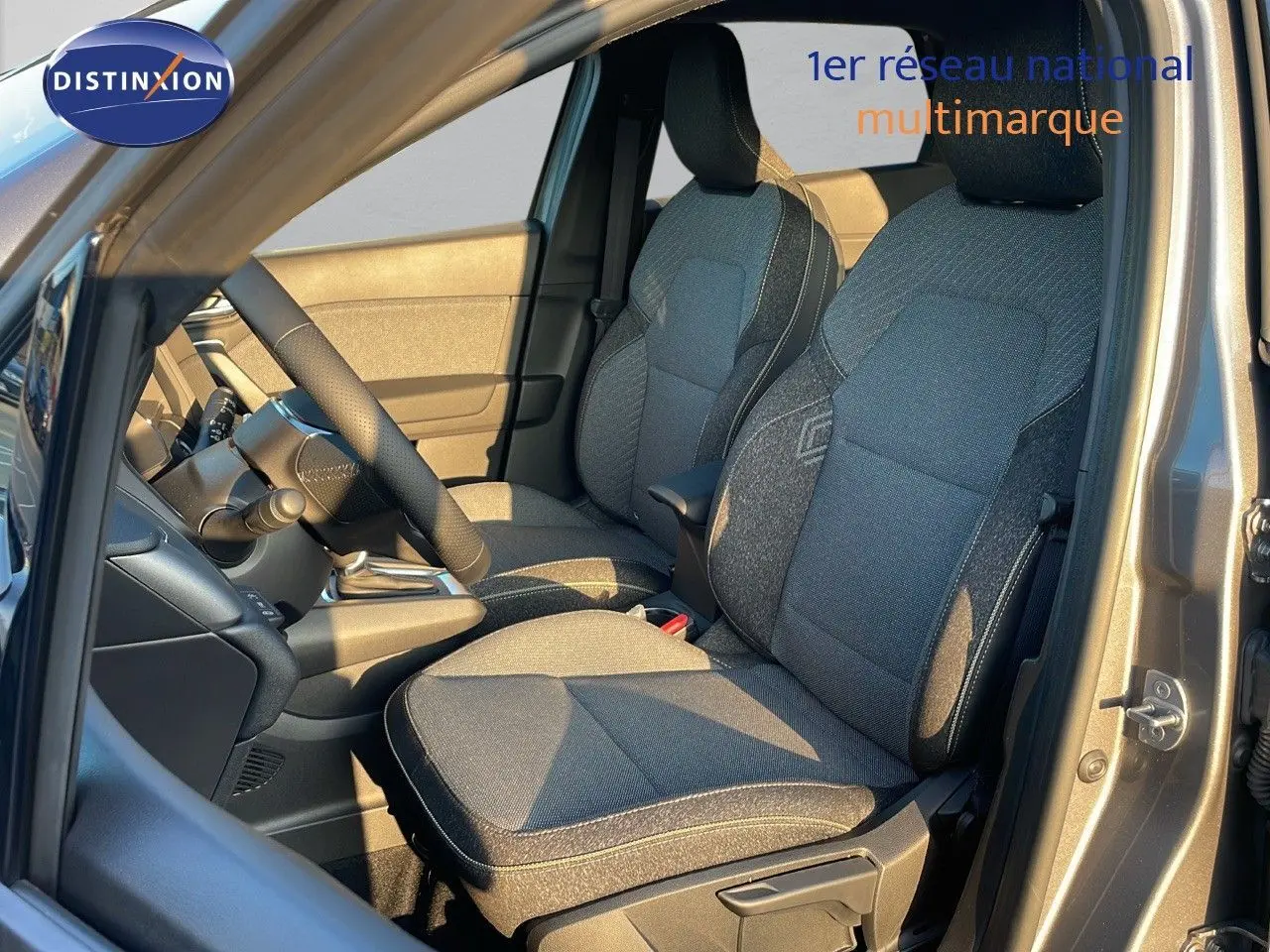 Intérieur avant du Renault Captur E-Tech gris cassiopée, sièges tissu noir et gris, volant et console visibles côté conducteur.