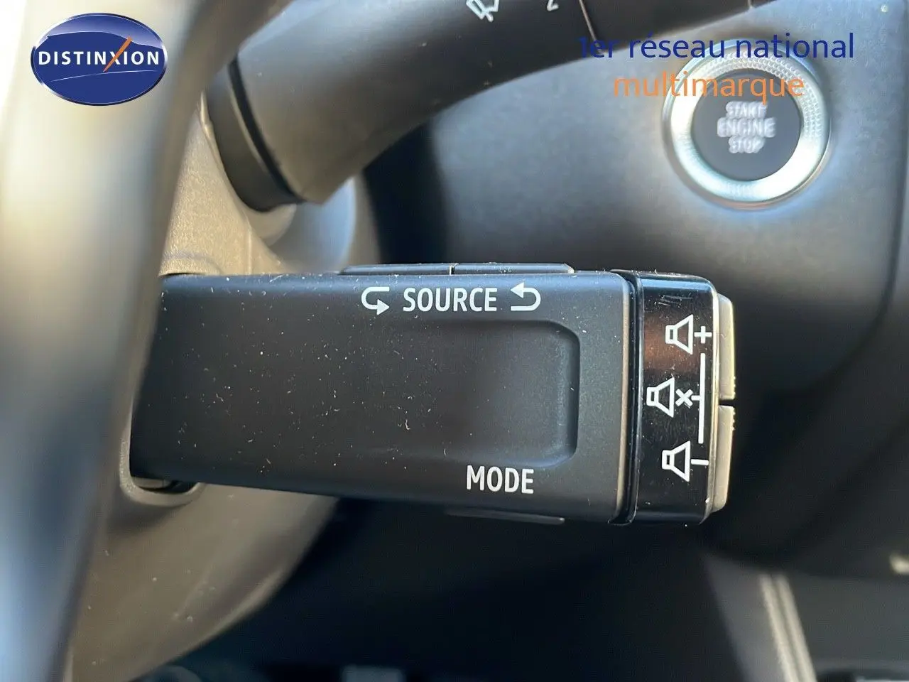 Gros plan sur la commande au volant du Renault Captur gris cassiopée, avec bouton source et mode, et démarrage sans clé visible.