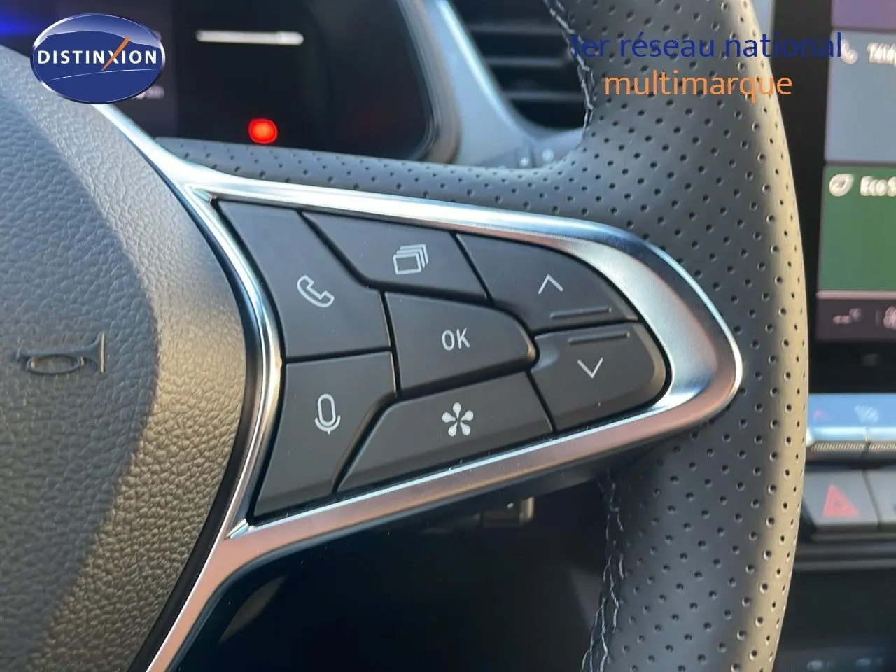 Gros plan sur les commandes multifonctions du volant perforé du Renault Captur gris Cassiopée 2025 hybride.