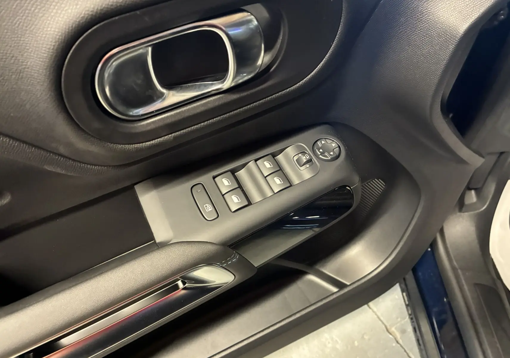 Gros plan sur la porte côté gauche du Citroën C5 Aircross 2025 bleu Eclipse Metal, montrant les commandes de vitres et la poignée intérieure chromée.
