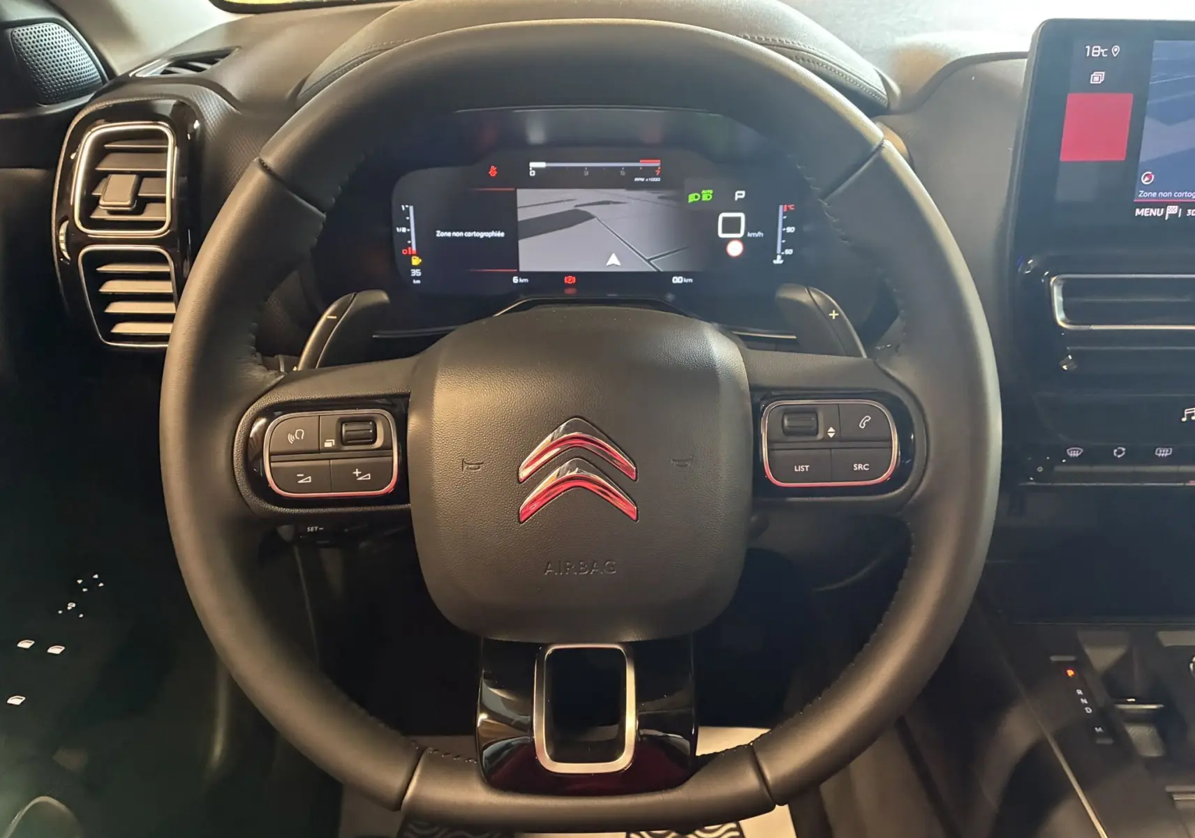 Vue rapprochée du volant cuir noir du Citroën C5 Aircross 2025 avec tableau de bord numérique et écran tactile central.