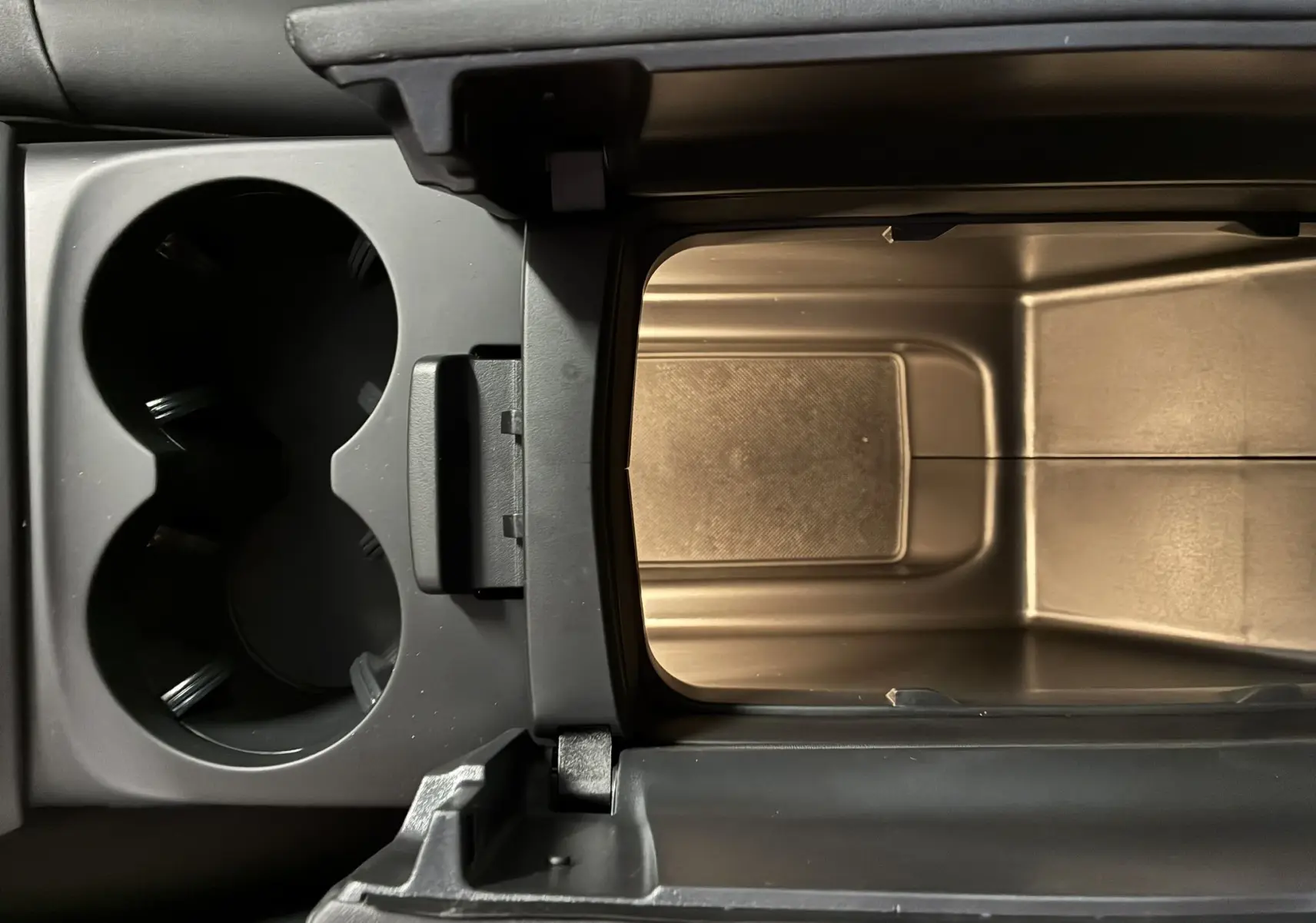 Vue rapprochée de la console centrale ouverte du Citroën C5 Aircross 2025, montrant les porte-gobelets et le rangement intérieur.