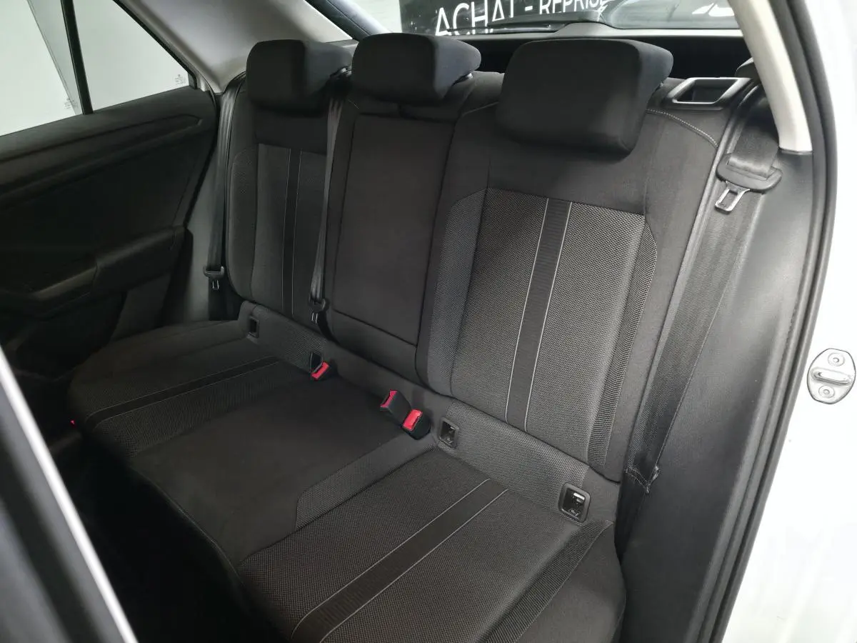 Vue intérieure de la banquette arrière noire du Volkswagen T-Roc blanc, avec ceintures de sécurité et appuis-tête visibles.
