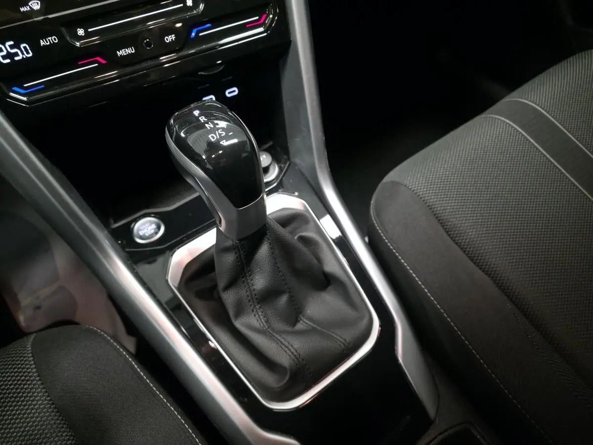 Gros plan sur la commande de boîte automatique noire entourée de cuir, avec sièges tissu gris du Volkswagen T-Roc 2022.