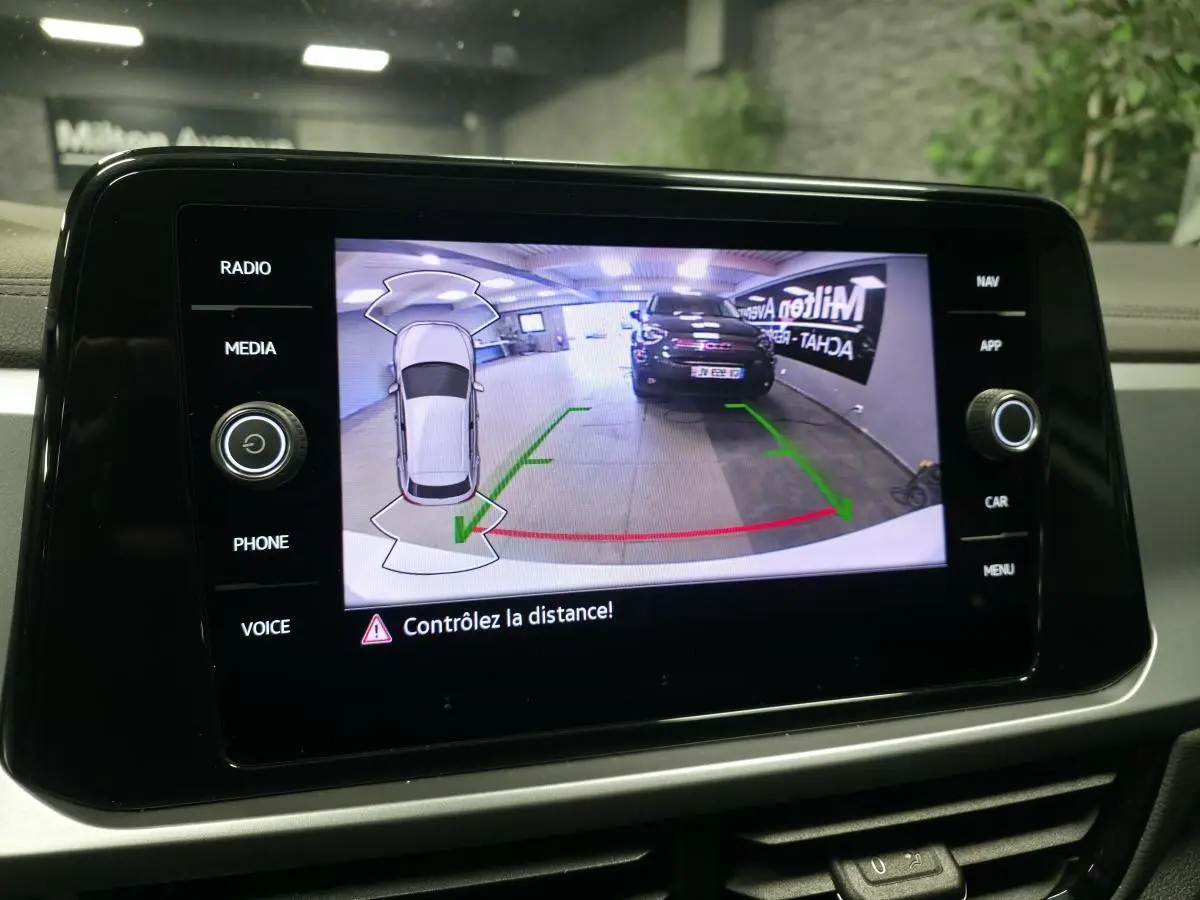 Écran tactile intérieur montrant la caméra de recul avec vue arrière d'un véhicule noir dans un garage.