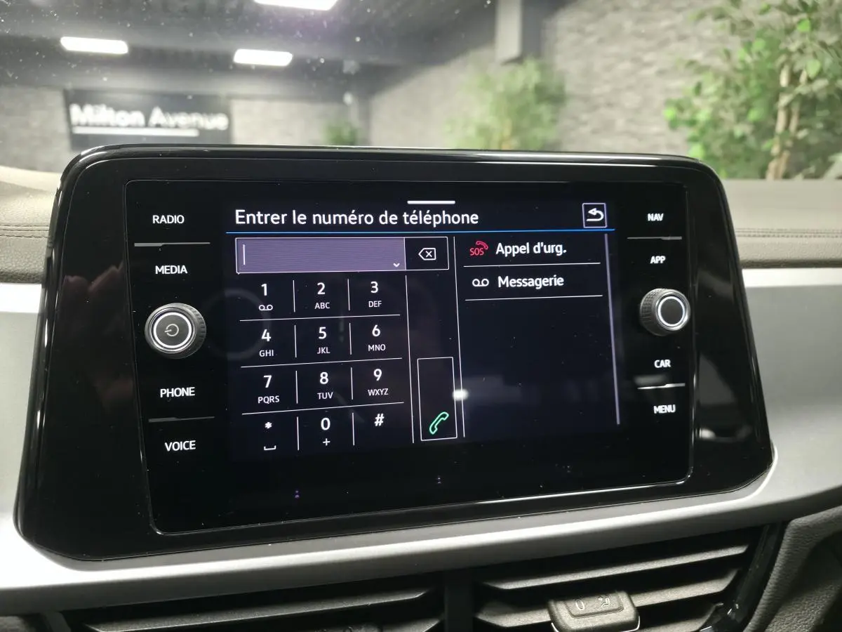 Écran tactile central du Volkswagen T-Roc blanc 2022 affichant le clavier pour entrer un numéro de téléphone.