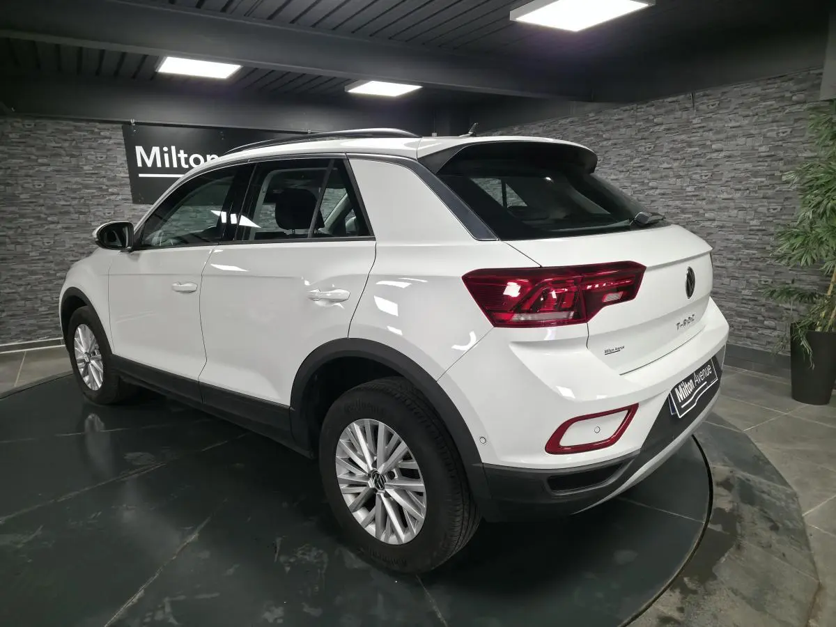 Volkswagen T-Roc blanc vu en 3/4 arrière droit, avec jantes alliage et feux arrière LED rouges.