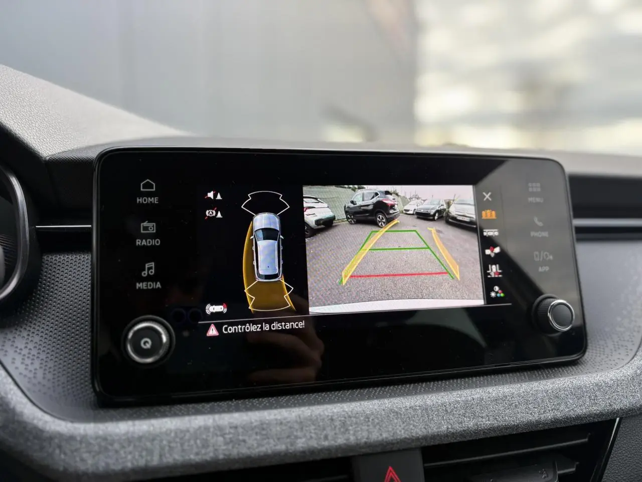 Écran central du Skoda Kamiq TSI 116 DSG7 gris argent montrant la caméra de recul et l'aide au stationnement.