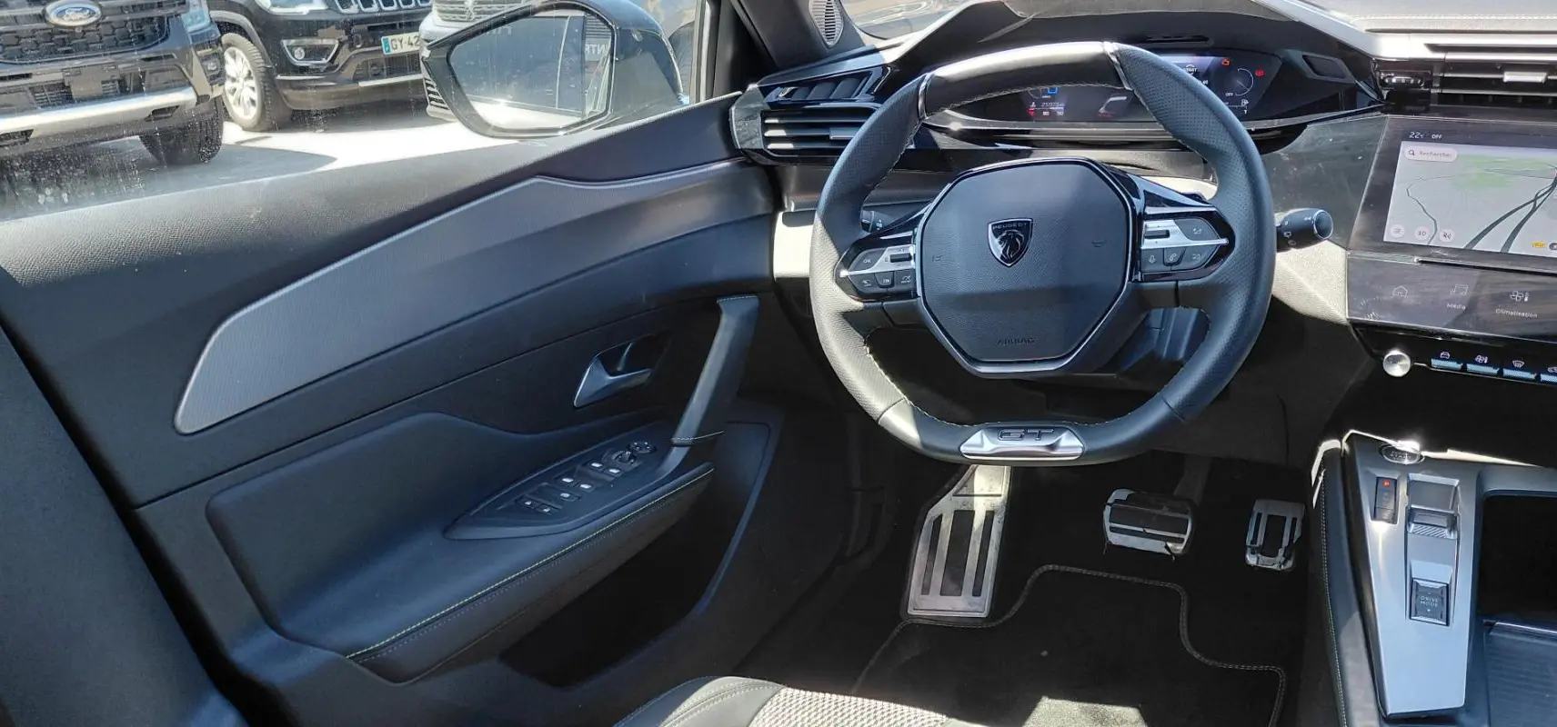 Vue intérieure côté conducteur de la Peugeot 308 Hybrid 145 GT 2025, volant cuir GT et cockpit numérique visibles.