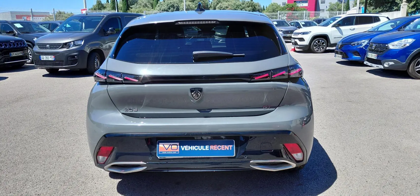Vue arrière d’une Peugeot 308 Hybrid 145 e-DCS6 GT gris avec feux LED et double sortie d’échappement intégrée.