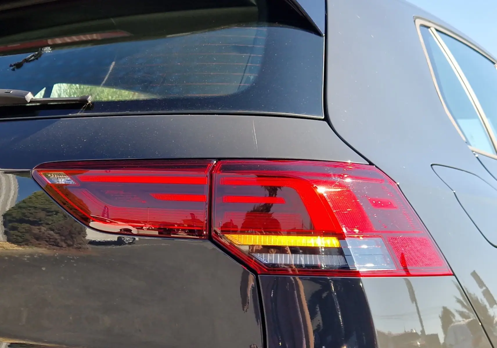 Gros plan sur le feu arrière droit rouge et orange d'une Volkswagen Golf A8 gris Urano 2023, vue arrière côté droit.