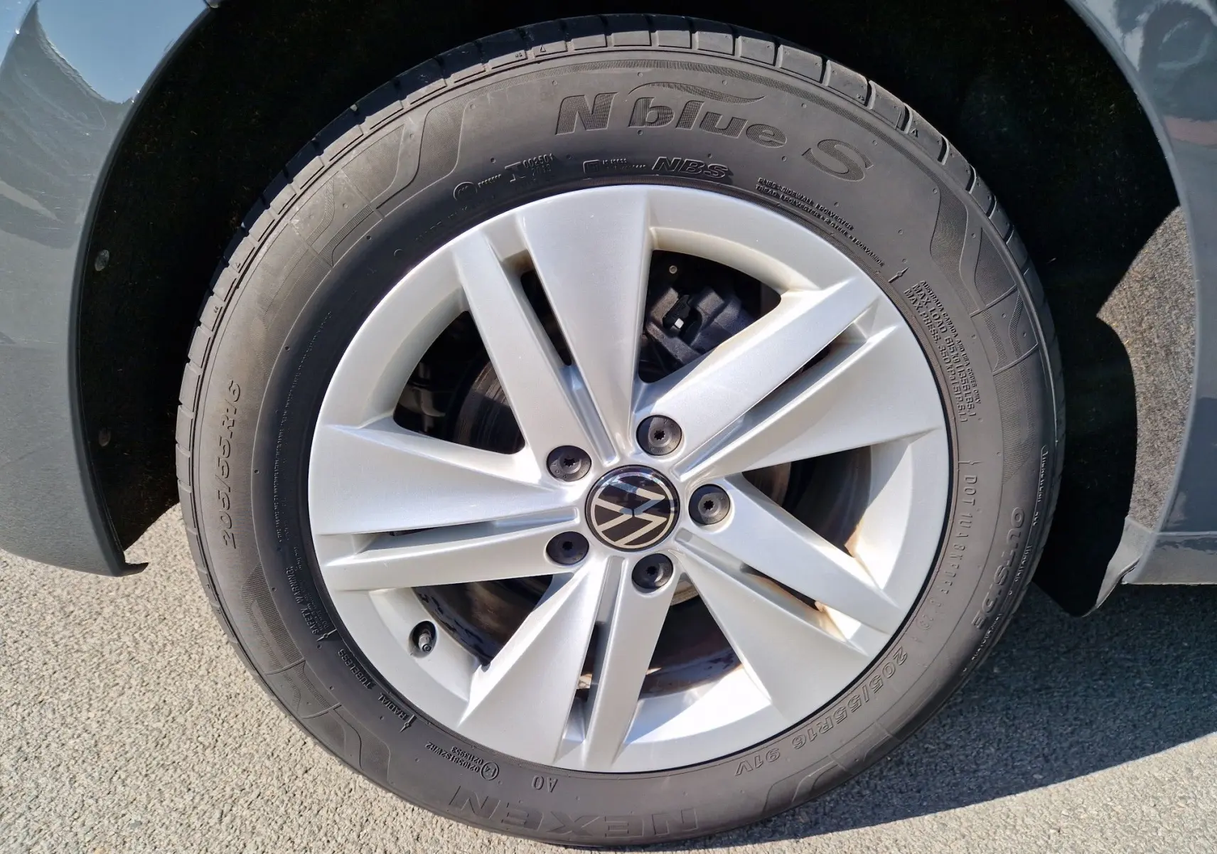 Gros plan sur la jante argentée et le pneu Nexen d'une Volkswagen Golf A8 gris Urano, détail du côté avant droit.
