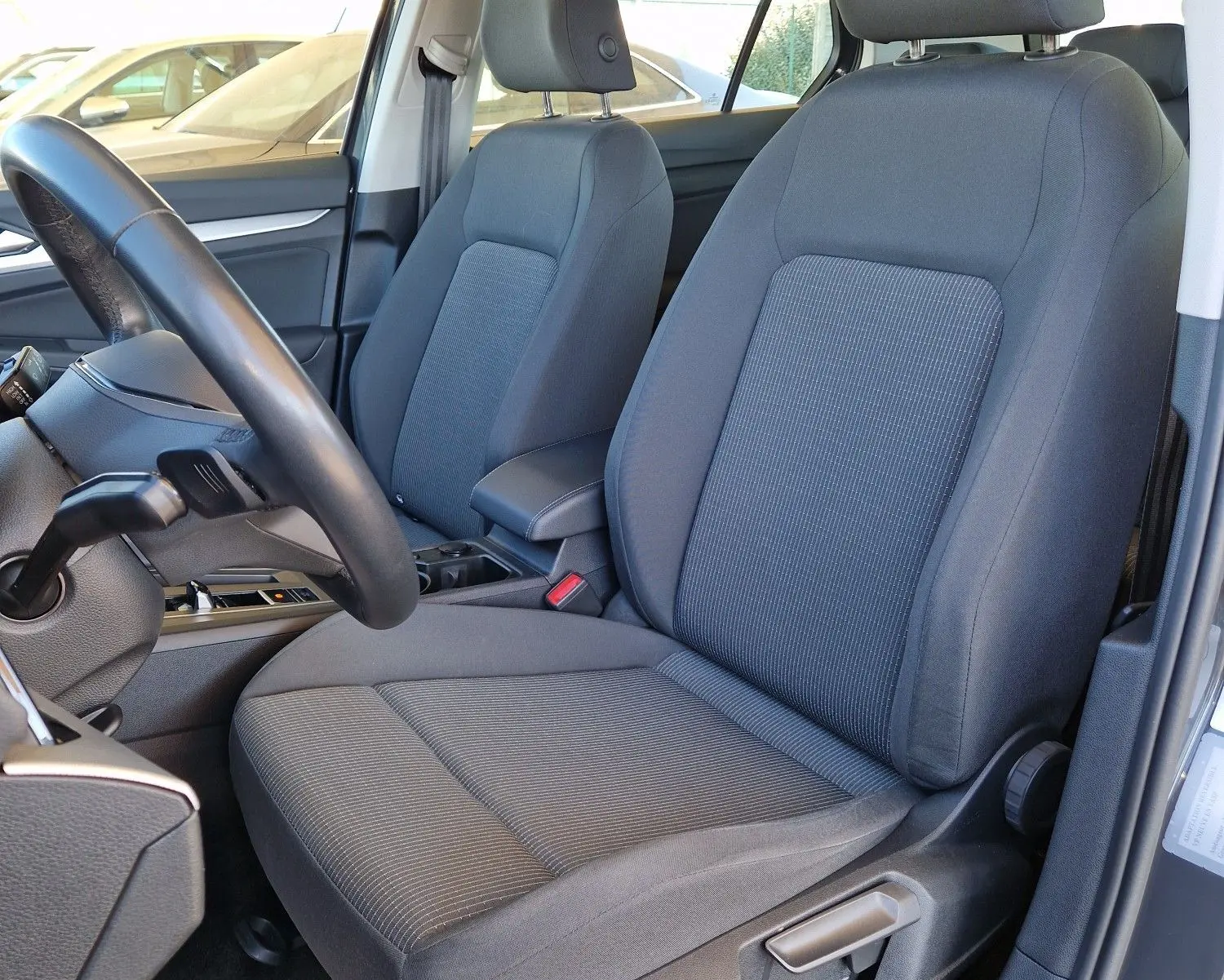 Vue intérieure côté conducteur de la Volkswagen Golf A8 gris Urano 2023, sièges tissu gris et volant noir visible.