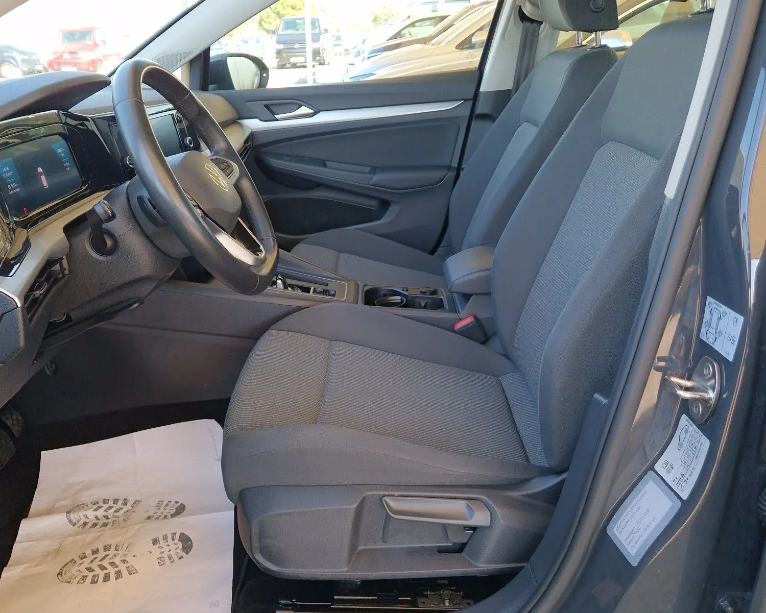 Intérieur côté conducteur d'une Volkswagen Golf A8 gris Urano 2023, sièges tissu gris et tableau de bord moderne.