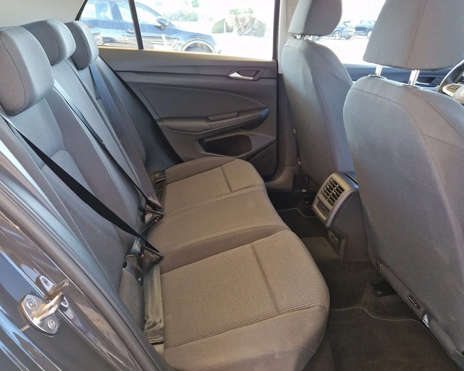 Vue intérieure côté gauche sur les sièges arrière gris d'une Volkswagen Golf A8 2.0 TDI 2023 avec ventilation centrale.