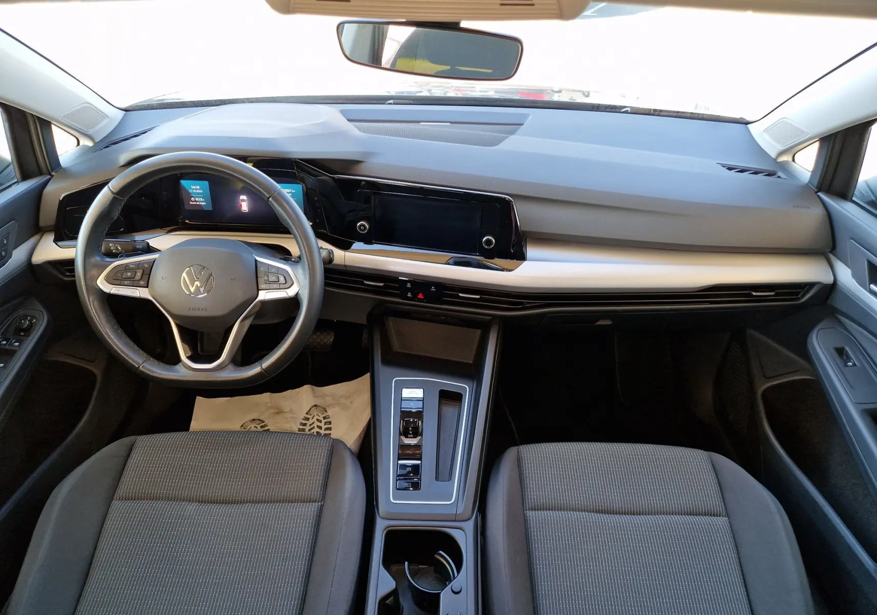 Vue intérieure avant de la Volkswagen Golf A8 2023 avec tableau de bord moderne et sièges gris, volant multifonction et écran tactile.