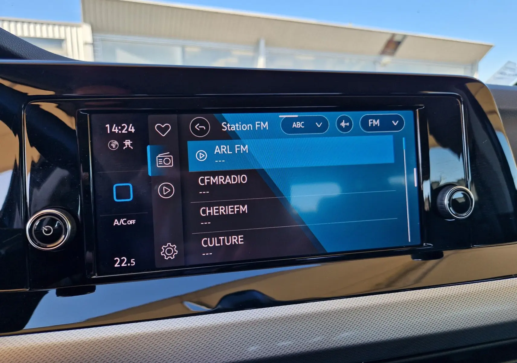 Écran tactile central de la Volkswagen Golf A8 2023 affichant les stations FM, avec finition intérieure noire brillante.