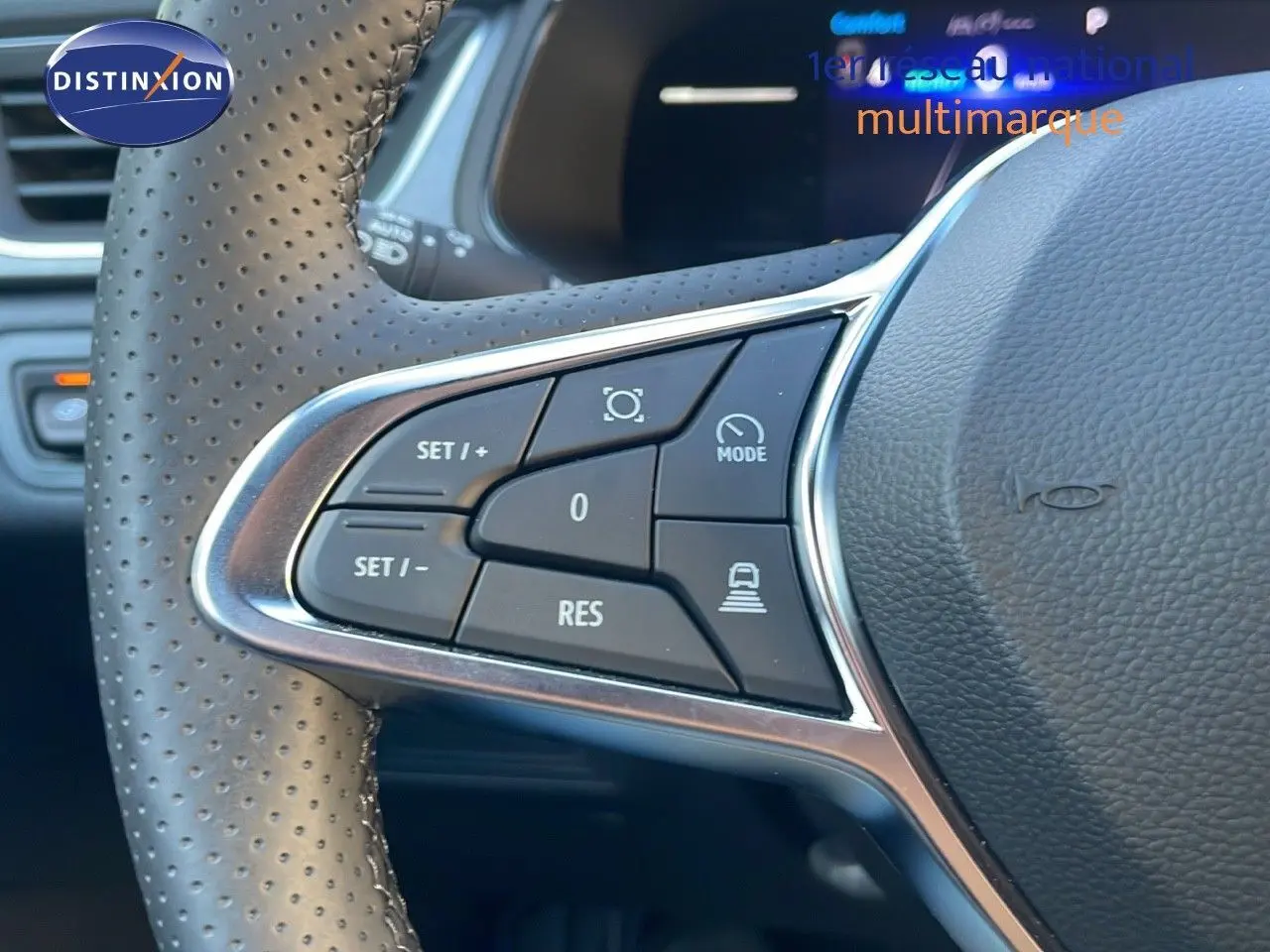 Gros plan sur les commandes au volant perforé du Renault Captur E-Tech gris Cassiopée, mettant en valeur les boutons de régulateur.