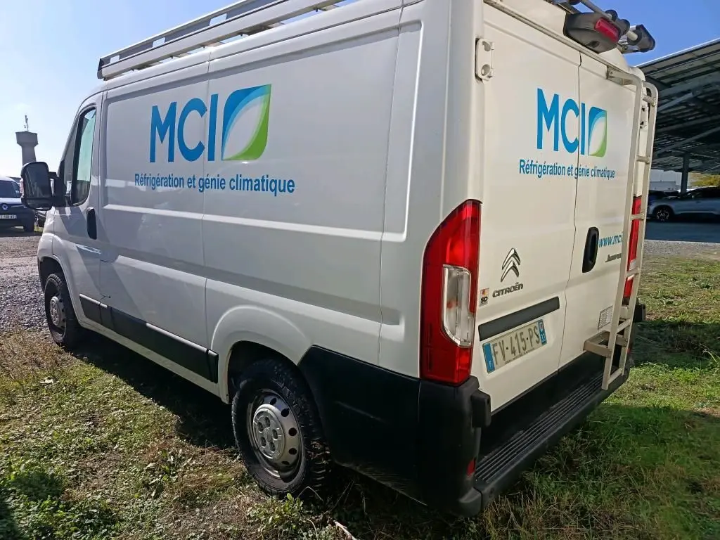 Vue 3/4 arrière droite d'un utilitaire blanc Citroën Jumper L1H1 avec logo MCI et galerie sur le toit.
