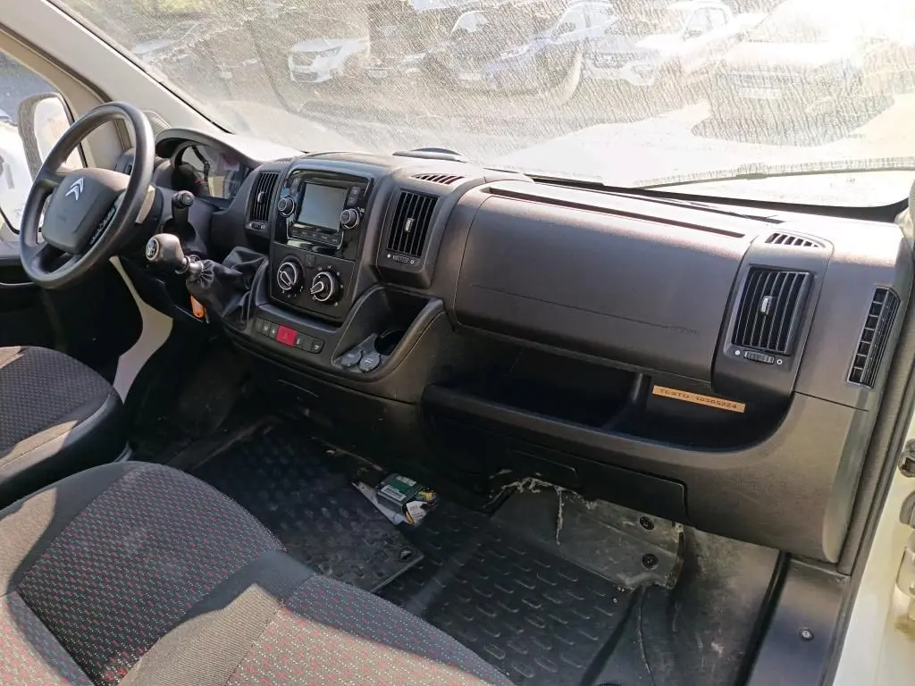 Vue intérieure côté conducteur du tableau de bord noir du Citroën Jumper blanc avec commandes manuelles et écran central.