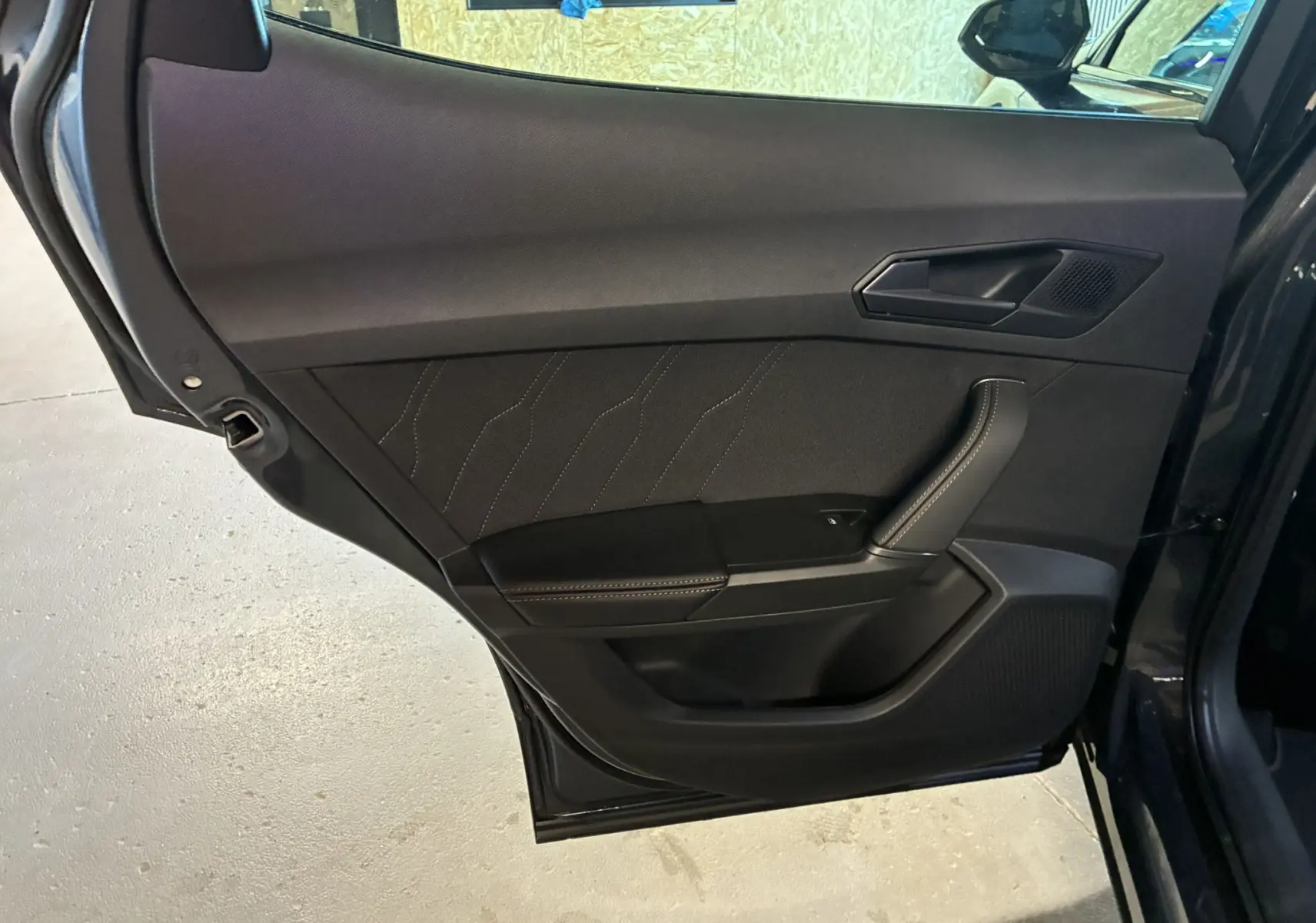 Porte arrière côté gauche ouverte d'un CUPRA Formentor gris foncé, intérieur noir avec surpiqûres contrastées.