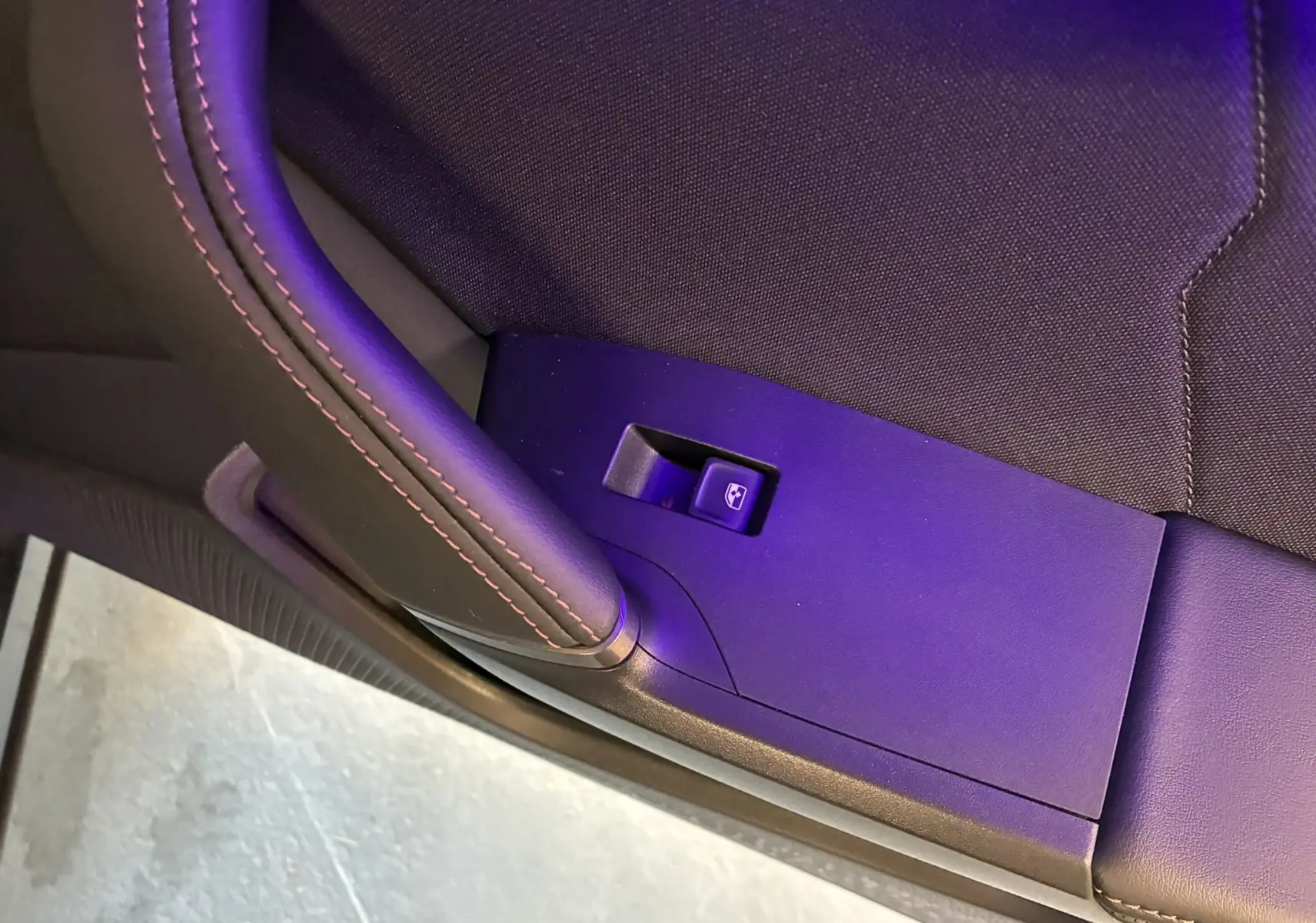 Gros plan sur le bouton de lève-vitre côté gauche avec surpiqûres rouges sur le panneau noir du CUPRA Formentor gris foncé 2024.