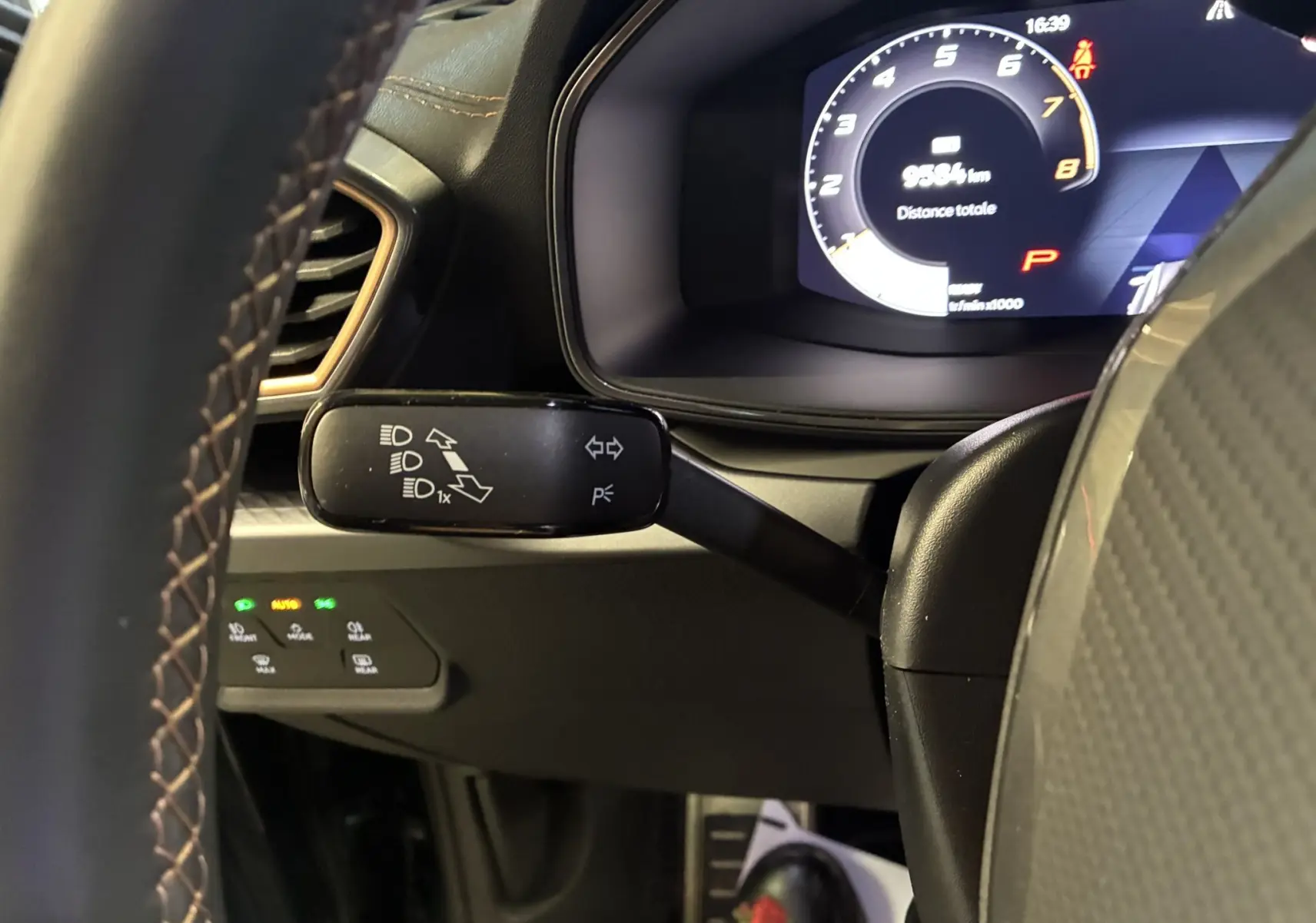 Gros plan sur le levier de clignotant et le tableau de bord numérique du CUPRA Formentor gris foncé, intérieur noir.