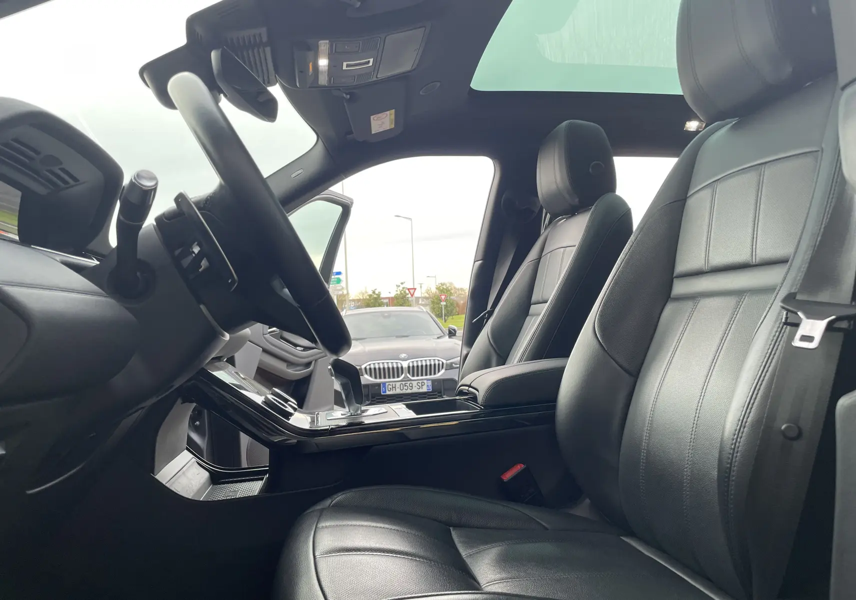 Vue intérieure côté conducteur du Range Rover Evoque 200D SE R-Dynamic 2021 avec sièges cuir noir et toit panoramique.