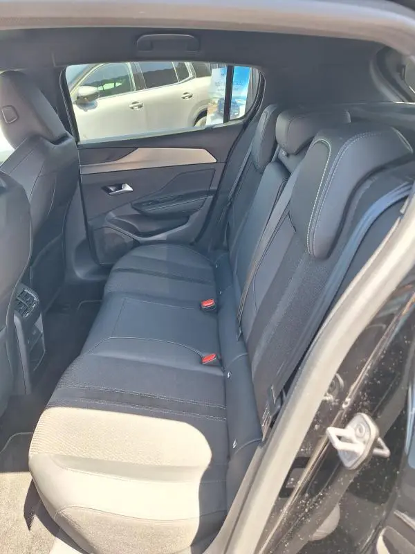 Vue intérieure côté droit sur les sièges arrière noirs de la Peugeot 308 Hybrid 145 e-DCS6 GT 2025 avec finitions tissu et cuir.