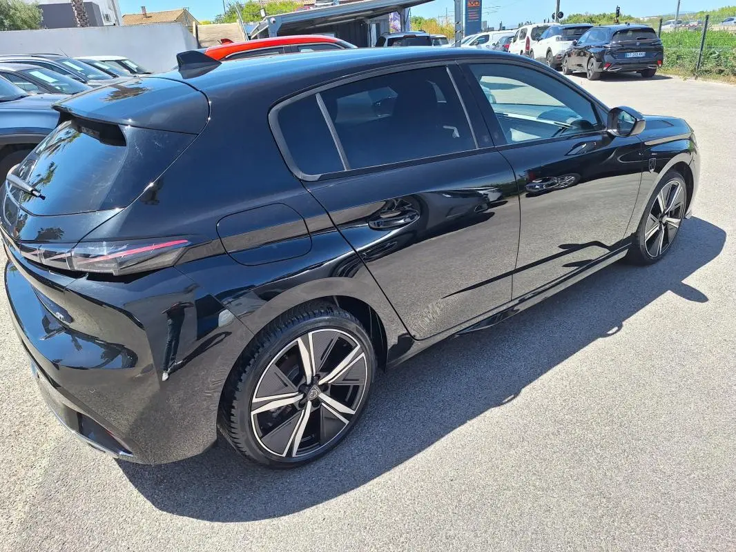 Peugeot 308 Hybrid 145 GT noir vue 3/4 arrière droit, jantes alliage 18 pouces et vitres teintées.