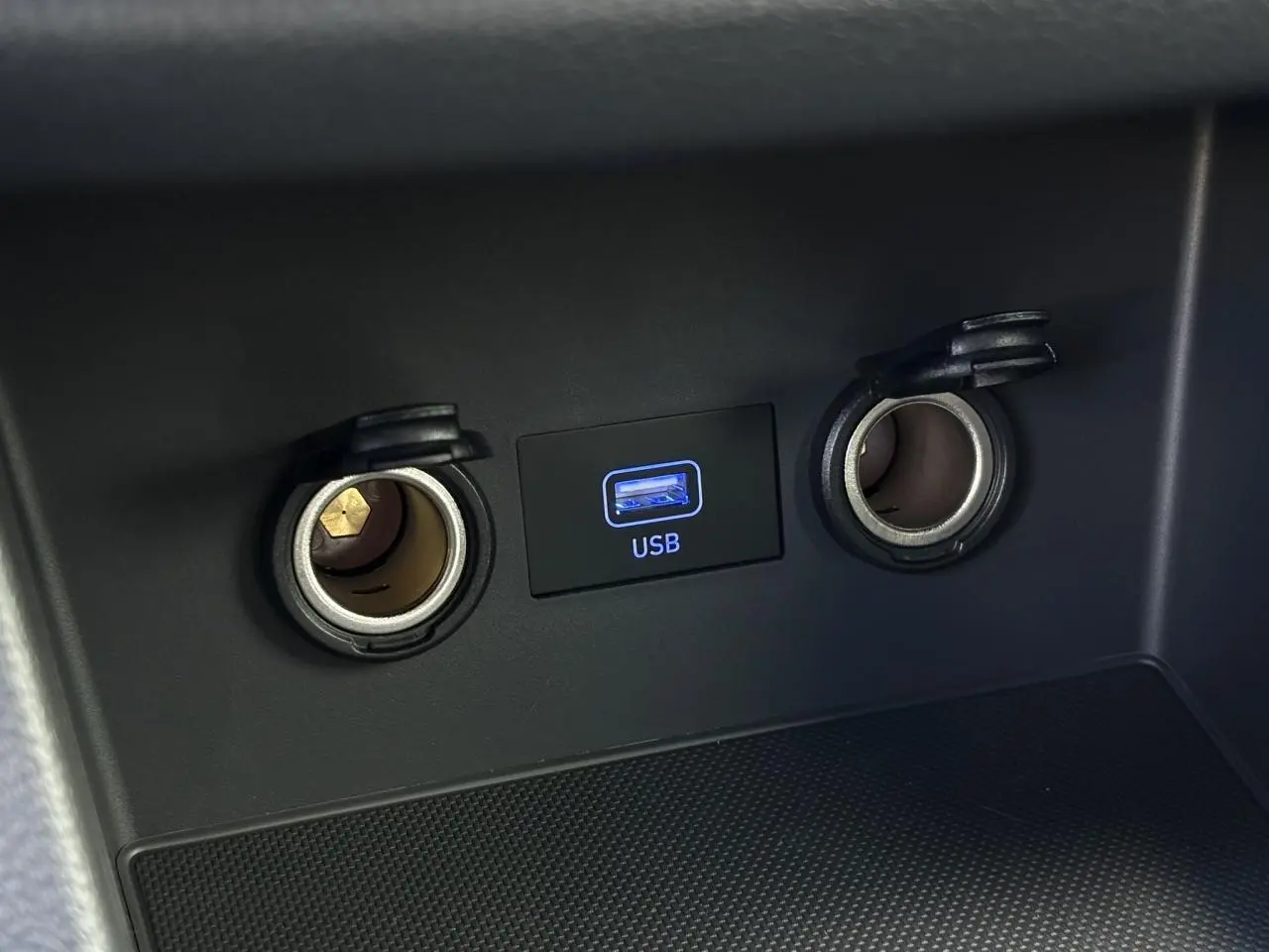 Vue rapprochée du port USB et des deux prises 12V avec couvercles ouverts dans l’habitacle d’une Hyundai i30 SW gris argent.