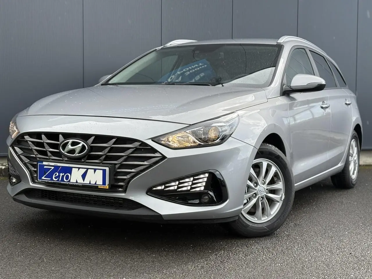 Hyundai i30 SW T-GDI 120 Modern gris argent en 3/4 avant droit, avec calandre noire et jantes alliage.