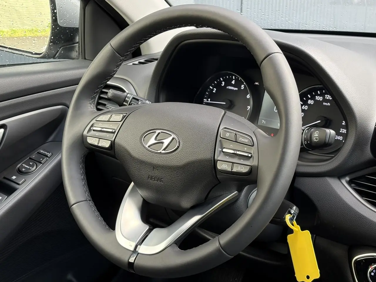 Vue rapprochée du volant cuir noir de la Hyundai i30 SW T-GDI 120 Modern 2025 avec commandes intégrées et tableau de bord visible.