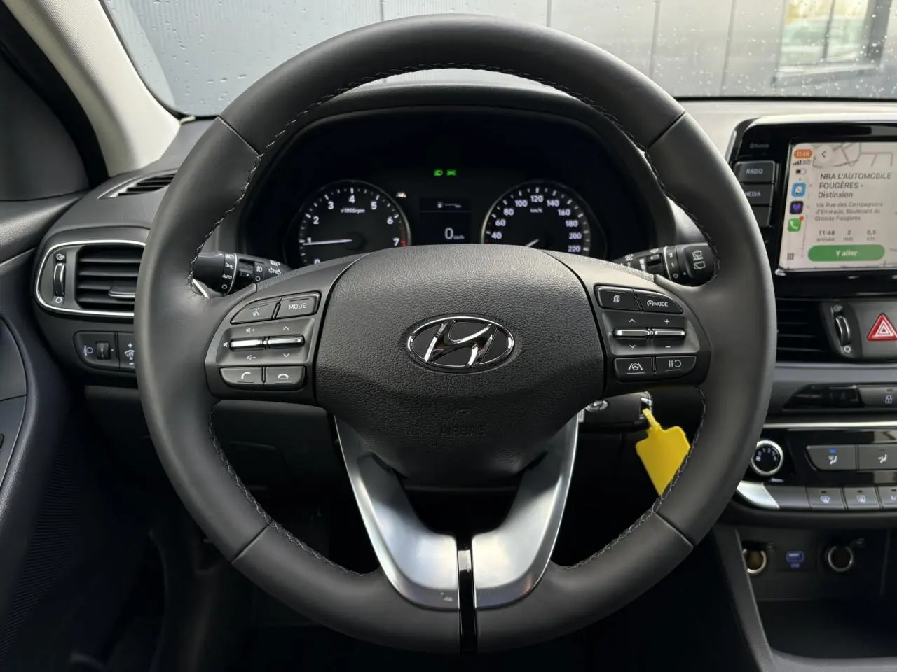 Vue intérieure centrée sur le volant cuir noir de la Hyundai i30 SW T-GDI 120 Modern avec tableau de bord et écran tactile.