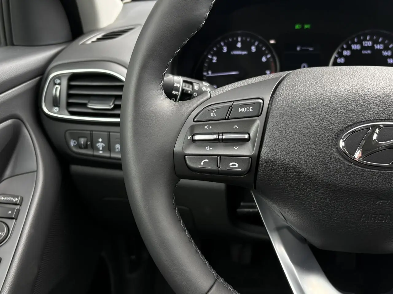 Gros plan sur le volant cuir noir de la Hyundai i30 SW T-GDI 120 Modern avec commandes multimédia intégrées.