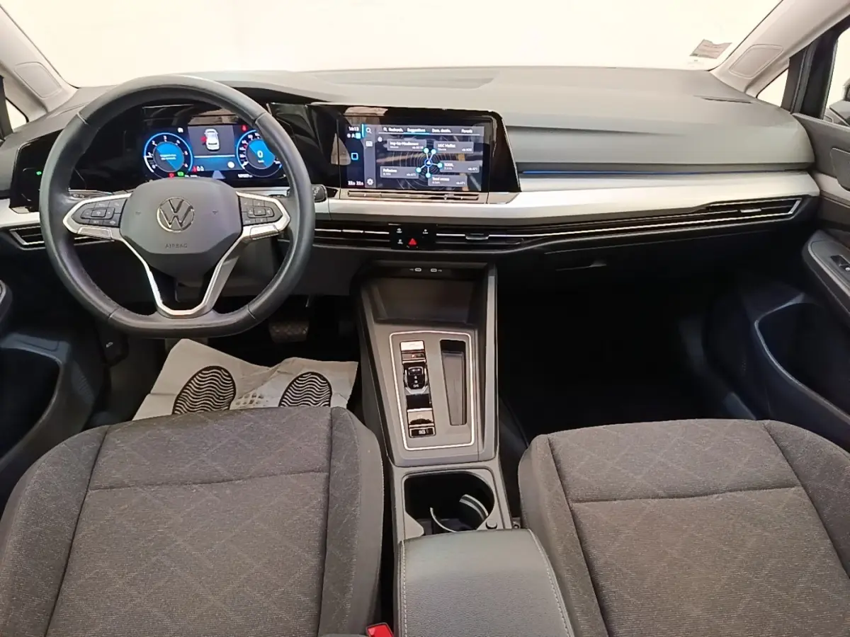 Vue intérieure avant de la Volkswagen Golf 2023 noire, tableau de bord digital et écran tactile central lumineux.