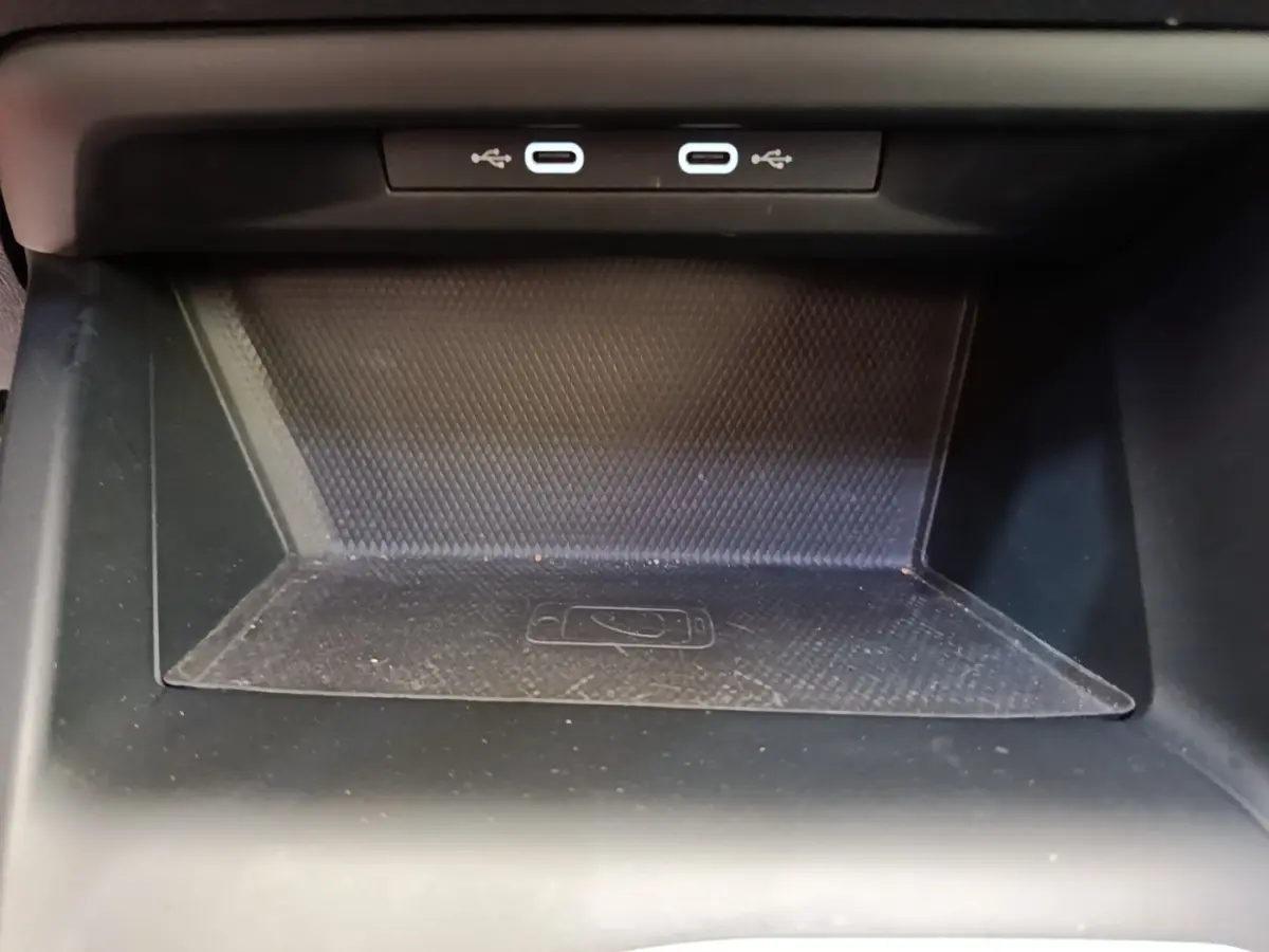Vue rapprochée de la zone de recharge à induction noire avec deux ports USB-C dans une Volkswagen Golf 2023.