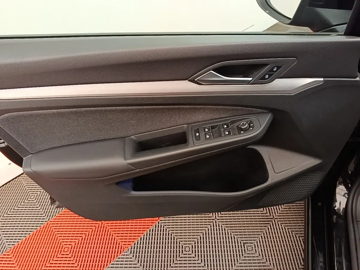 Vue rapprochée de la porte côté conducteur noire de la Volkswagen Golf 2023 avec commandes des vitres et verrouillage.