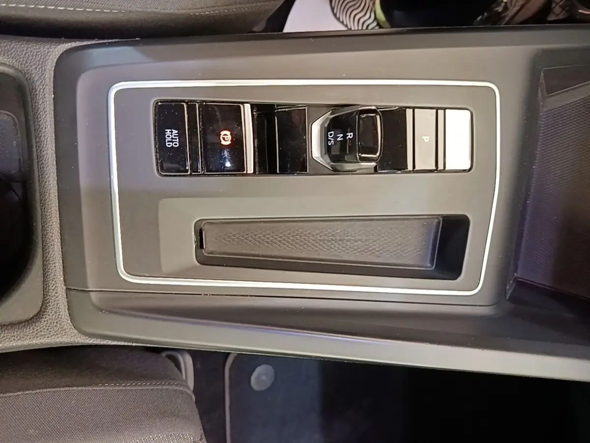 Vue plongeante sur la console centrale noire de la Volkswagen Golf 2023 avec boutons de frein à main électrique et sélecteur de vitesse.