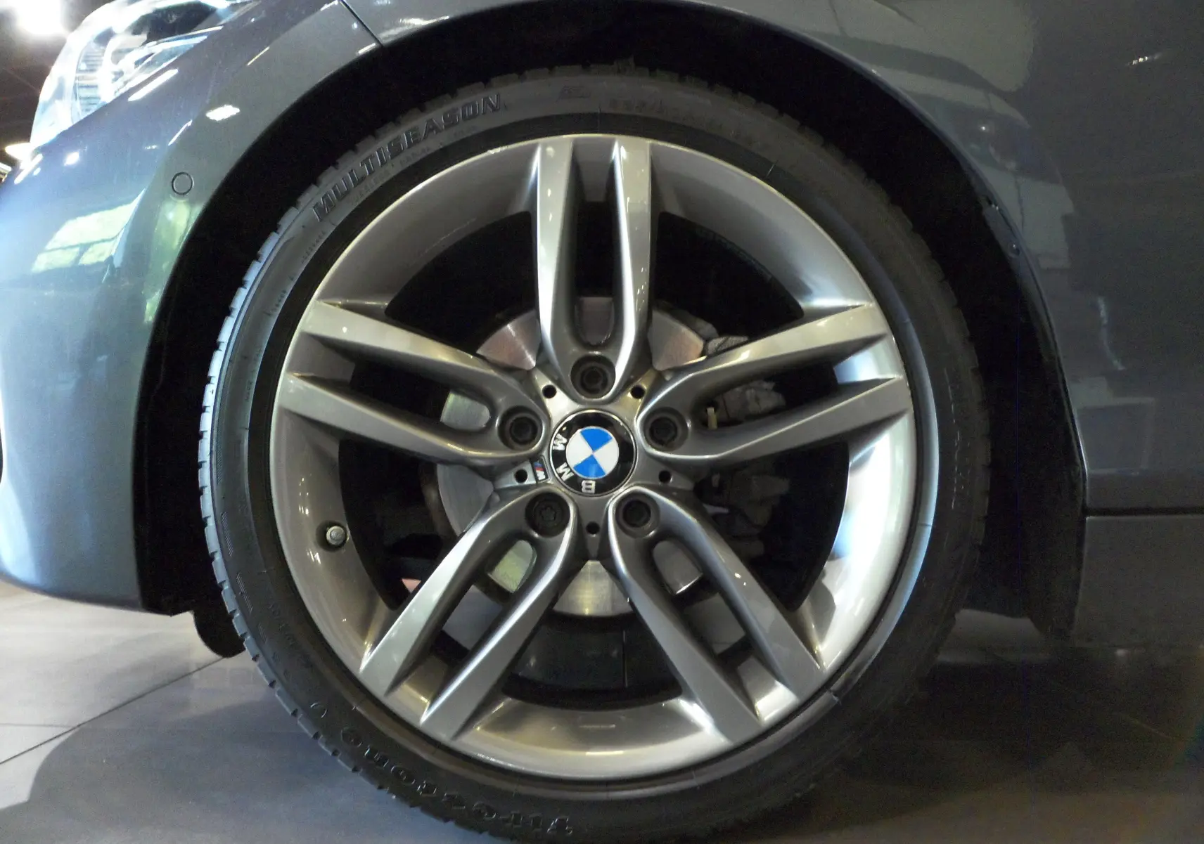 Gros plan sur la roue avant gauche gris métallisé d'une BMW Série 1 F21 LCI avec jante alliage 5 branches doubles.