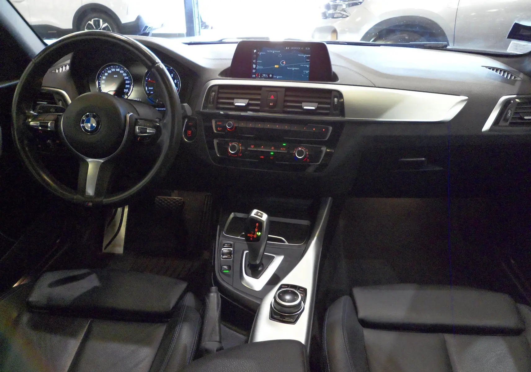 Intérieur de BMW Série 1 F21 LCI 118i 2019, vue du poste de conduite avec tableau de bord et console centrale en cuir noir.